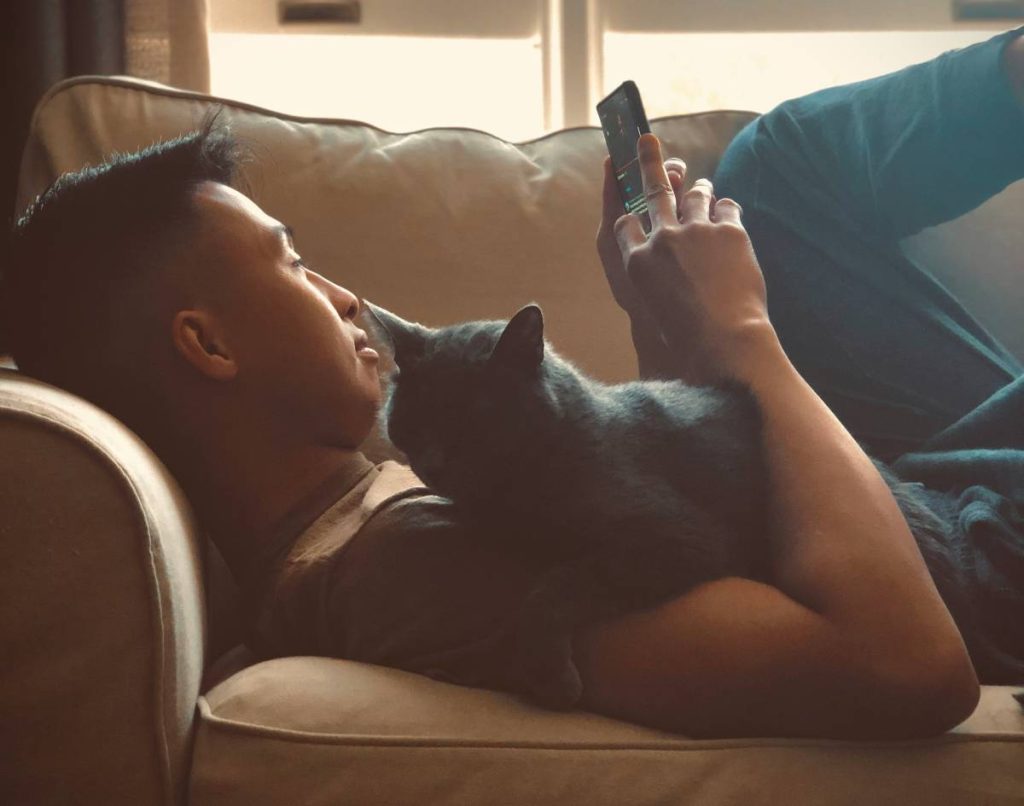 a man watching a video on his phone and holding a cat